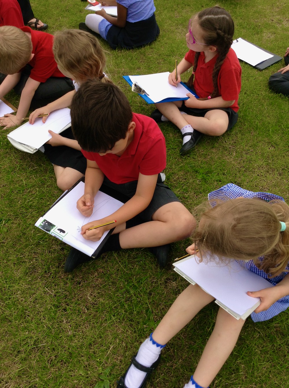 Children sat outdoors writing