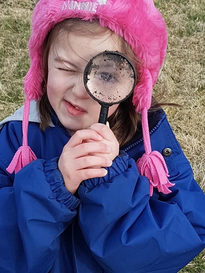 Child looking through magnifying glass