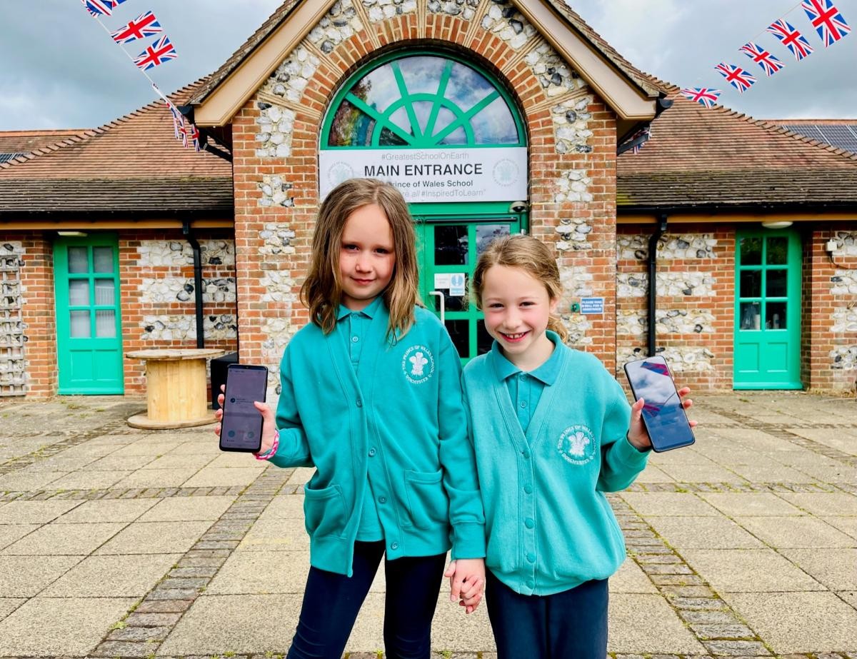 Two pupils outside the Prince of Wales School holding mobile phones