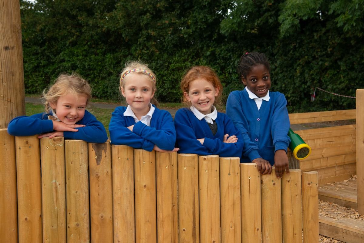 Children in a line looking over a fence