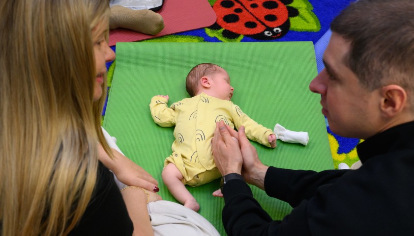 Two parents watch over their baby