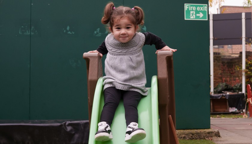 Little girl plays on a slide