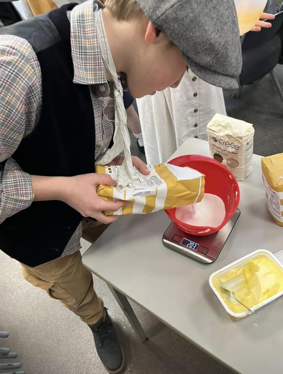 Learning to use electronic weighing scales to measure the ingredients needed to make a Victoria Sponge on Victorian Day.