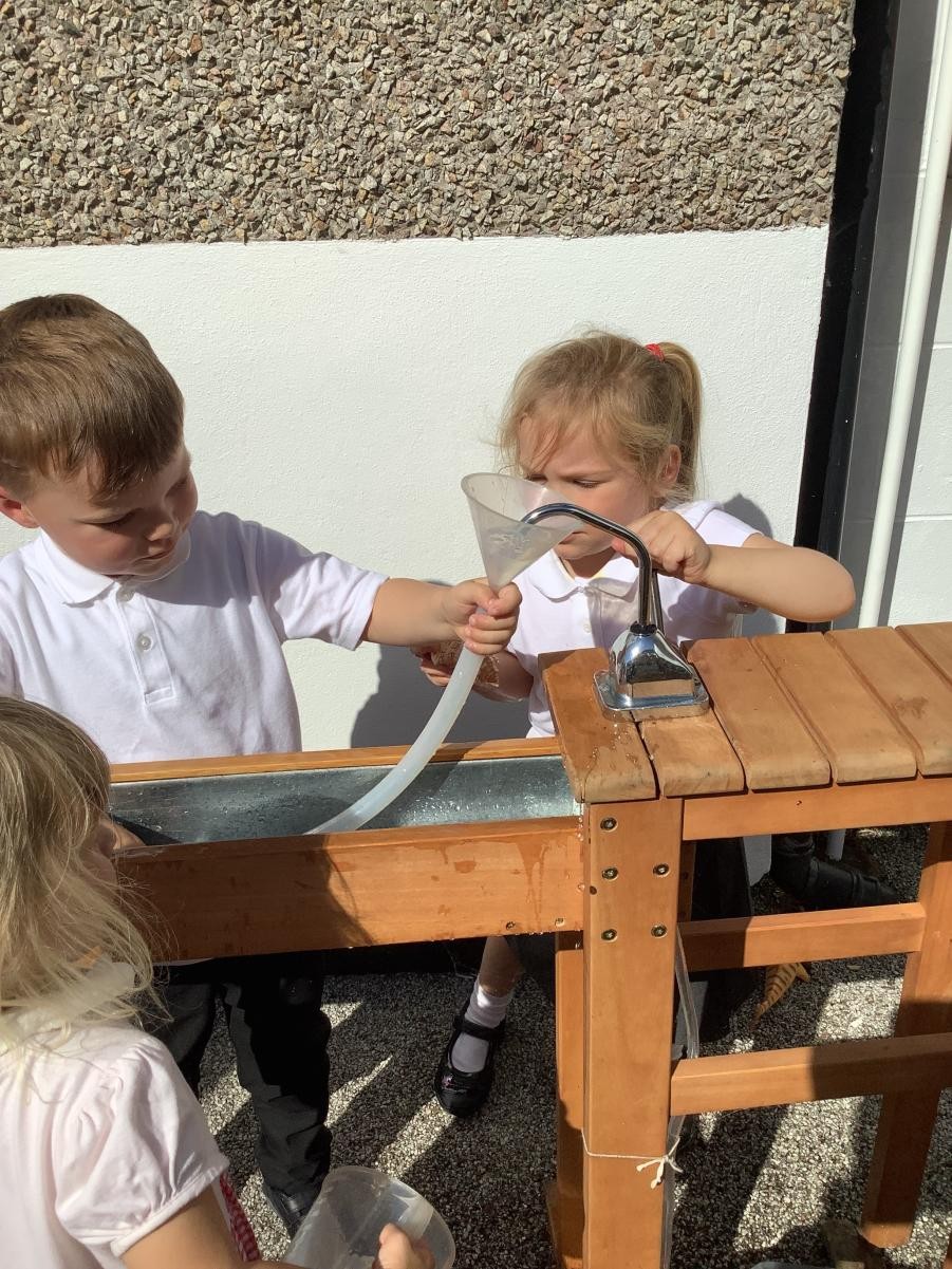 Outdoor Learning - Using our water pump to channel water into the water tray.