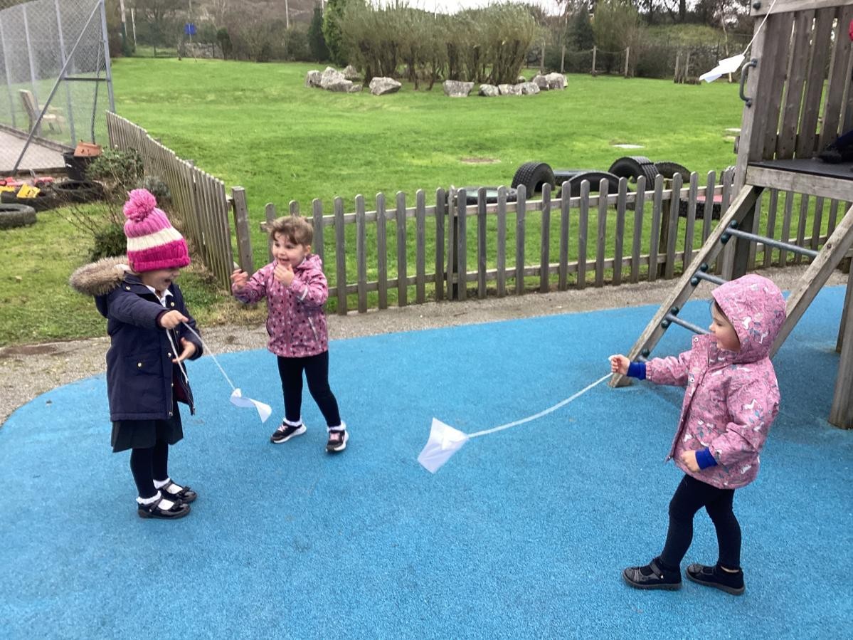 Children exploring a windy day by making and flying their own kites.