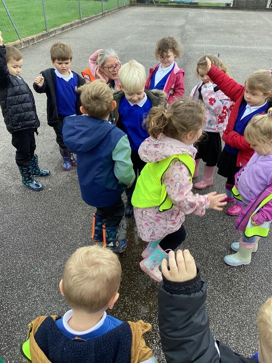 Nursery and reception children making the most of the wet weather to find puddles on a welly walk. 