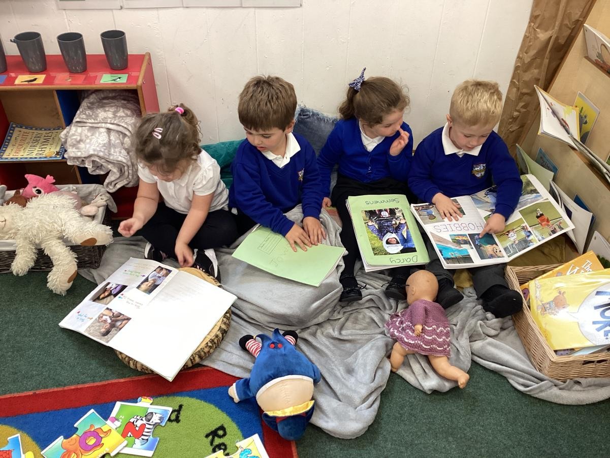 Nursery and reception children sharing their 'All About Me' books with each other. 