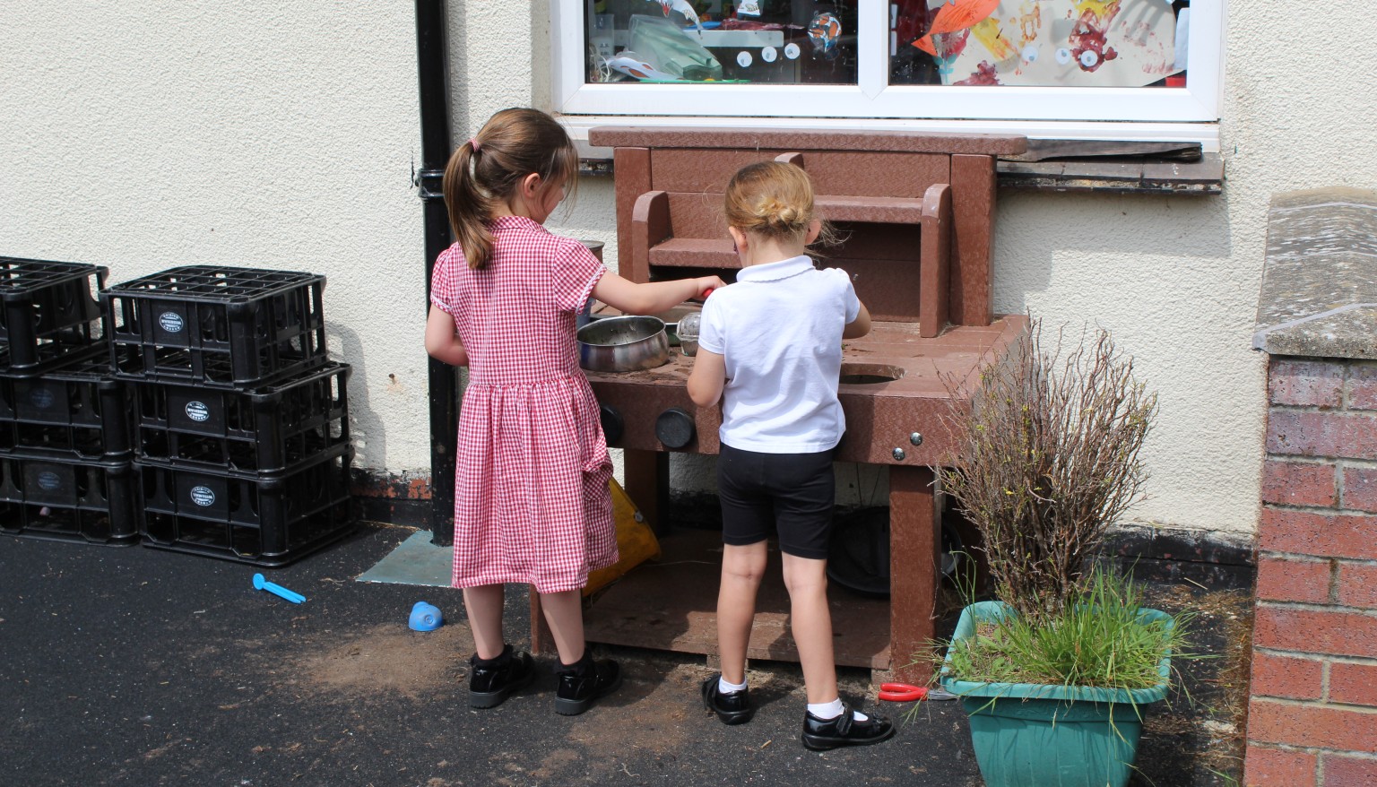Two children exploring a mud kitchen 