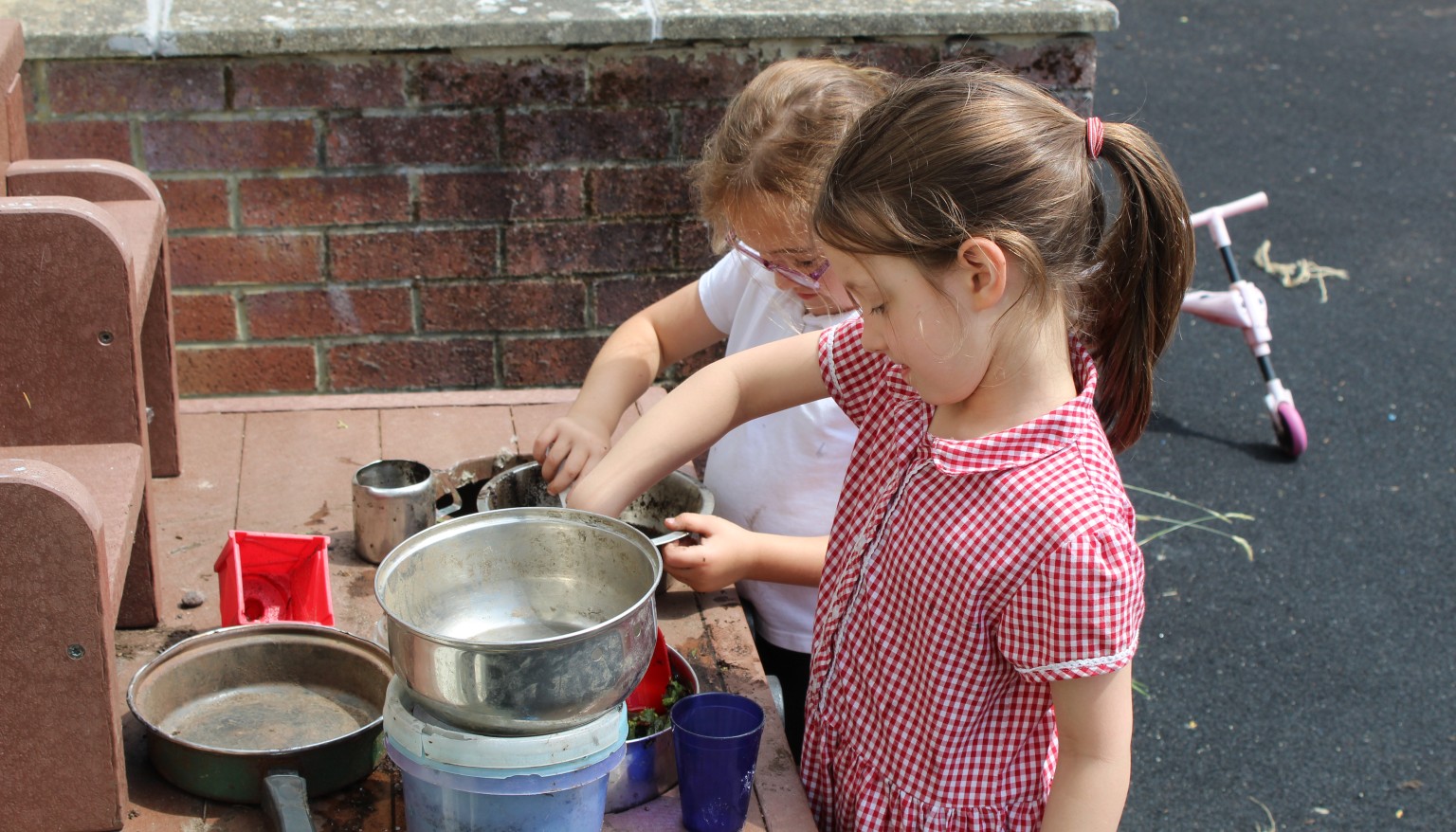 Two children exploring a mud kitchen 