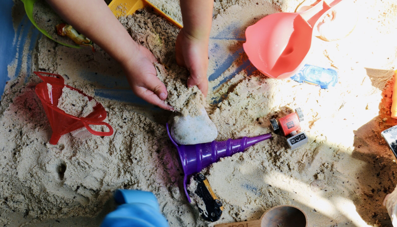childs hands in sand