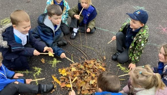 children outdoors holding sticks 