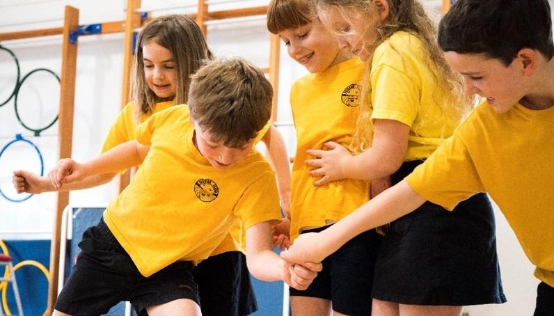 Children wearing yellow tops taking part in PE lesson 
