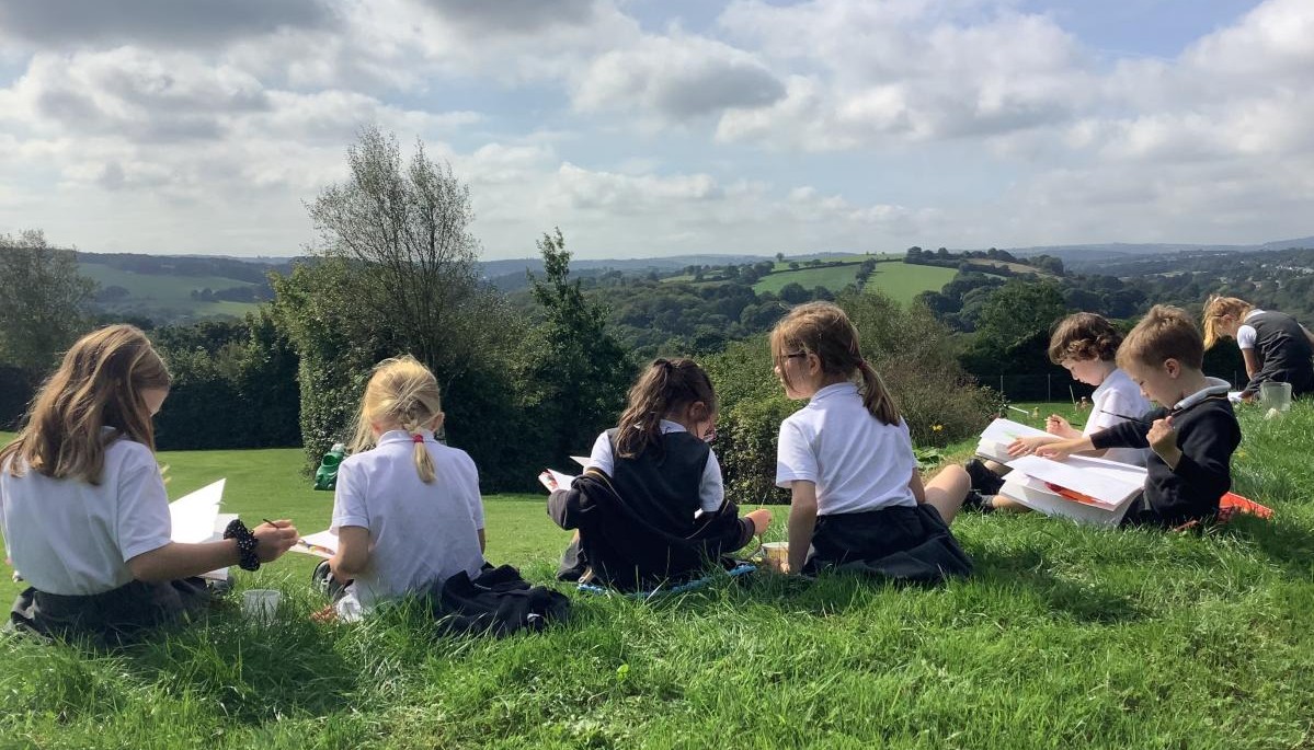 Children sat on a grassed hill 
