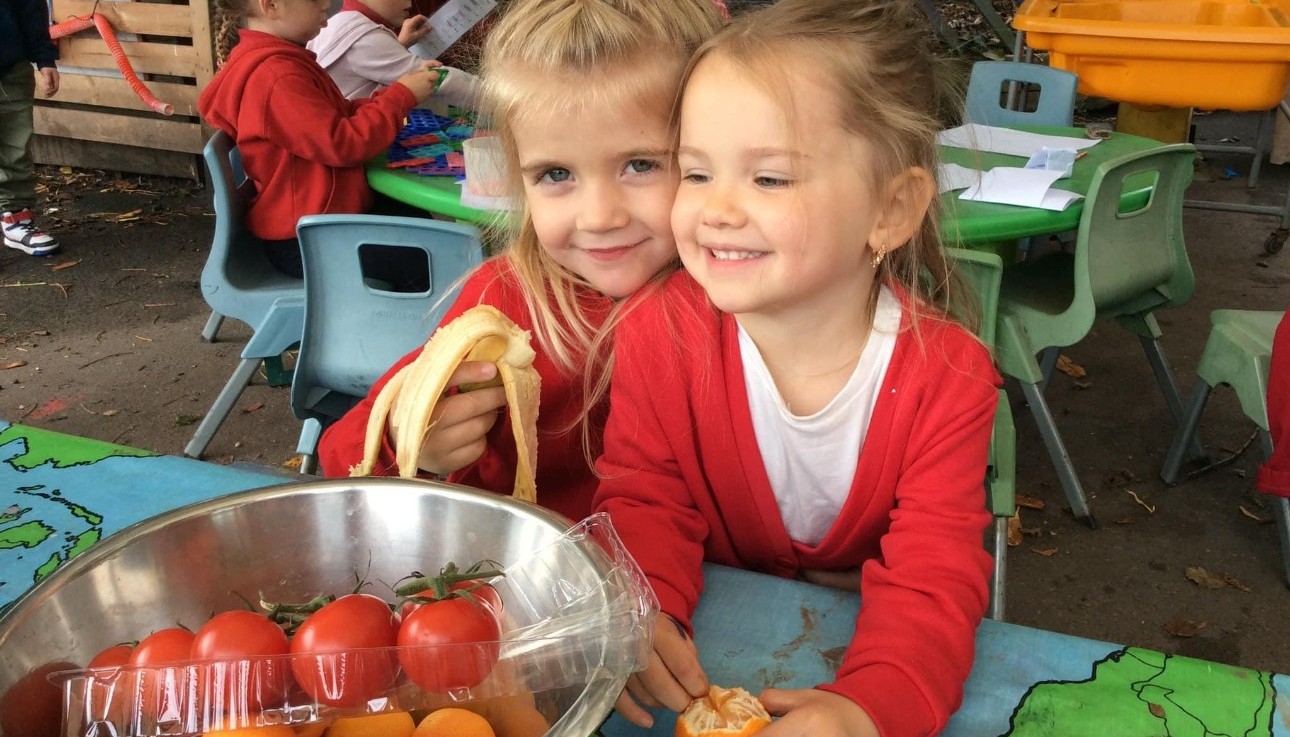 Two children smiling holding fruit 