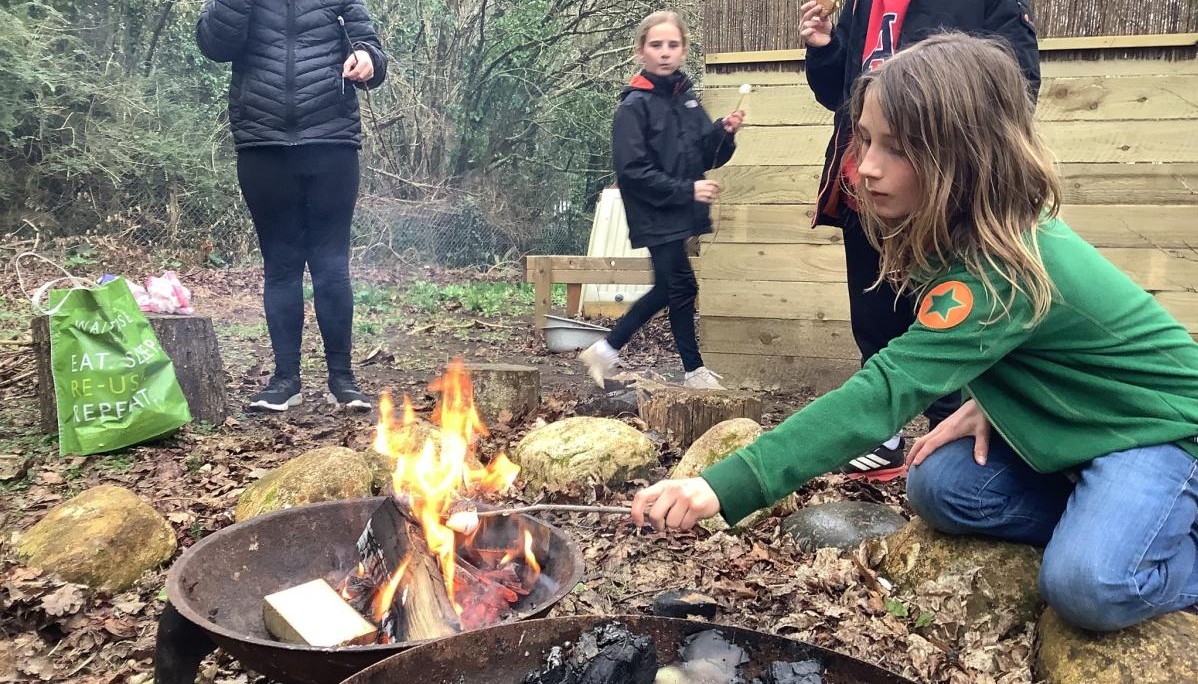 child holding a marshmallow over a fire pit