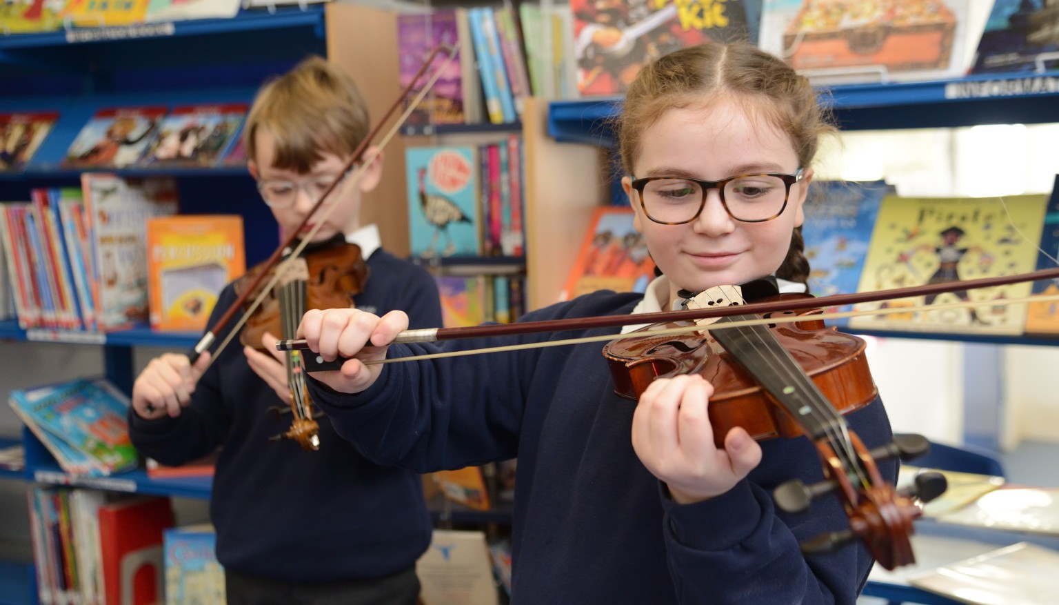 Two children playing violins