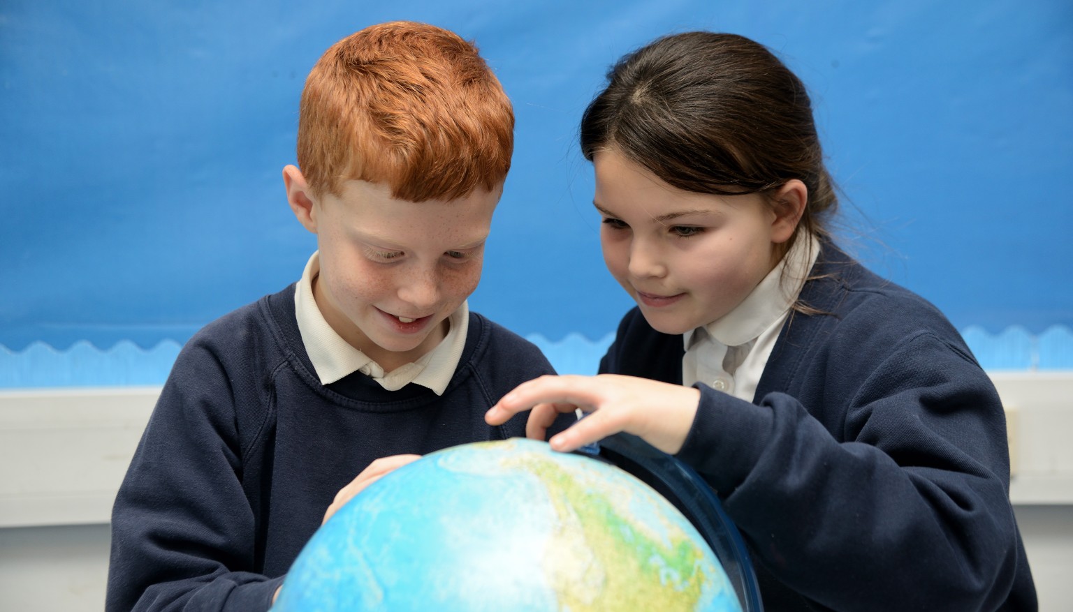 two children looking at a globe
