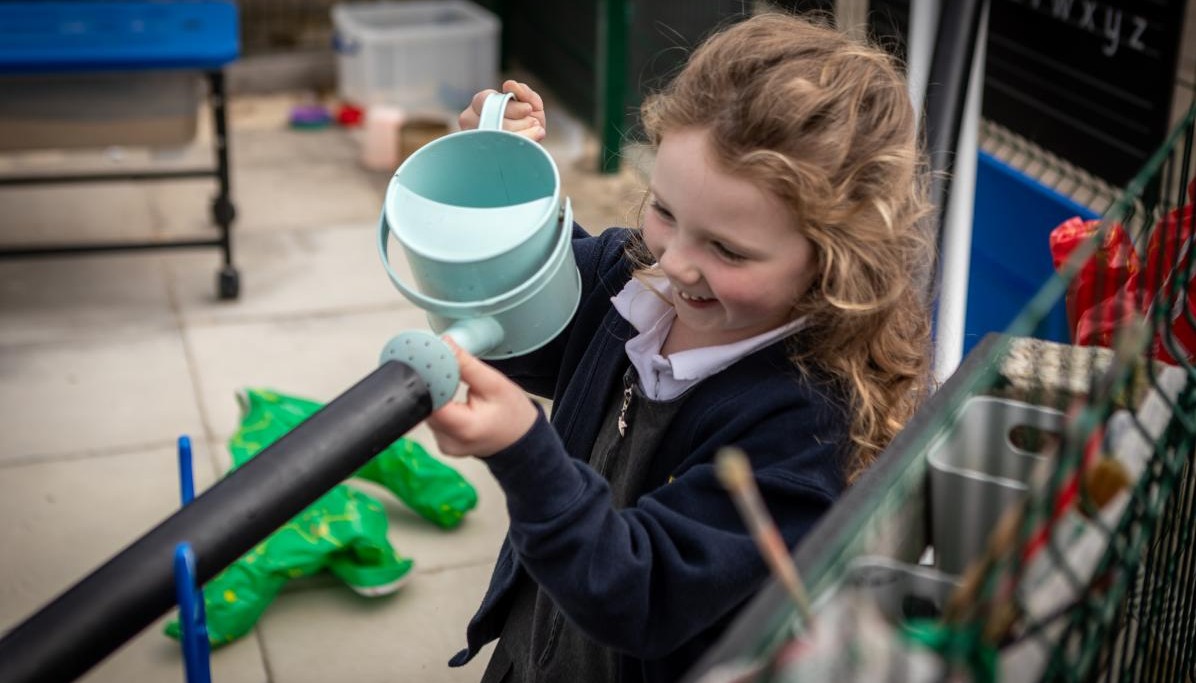 Child pouring with watering can 