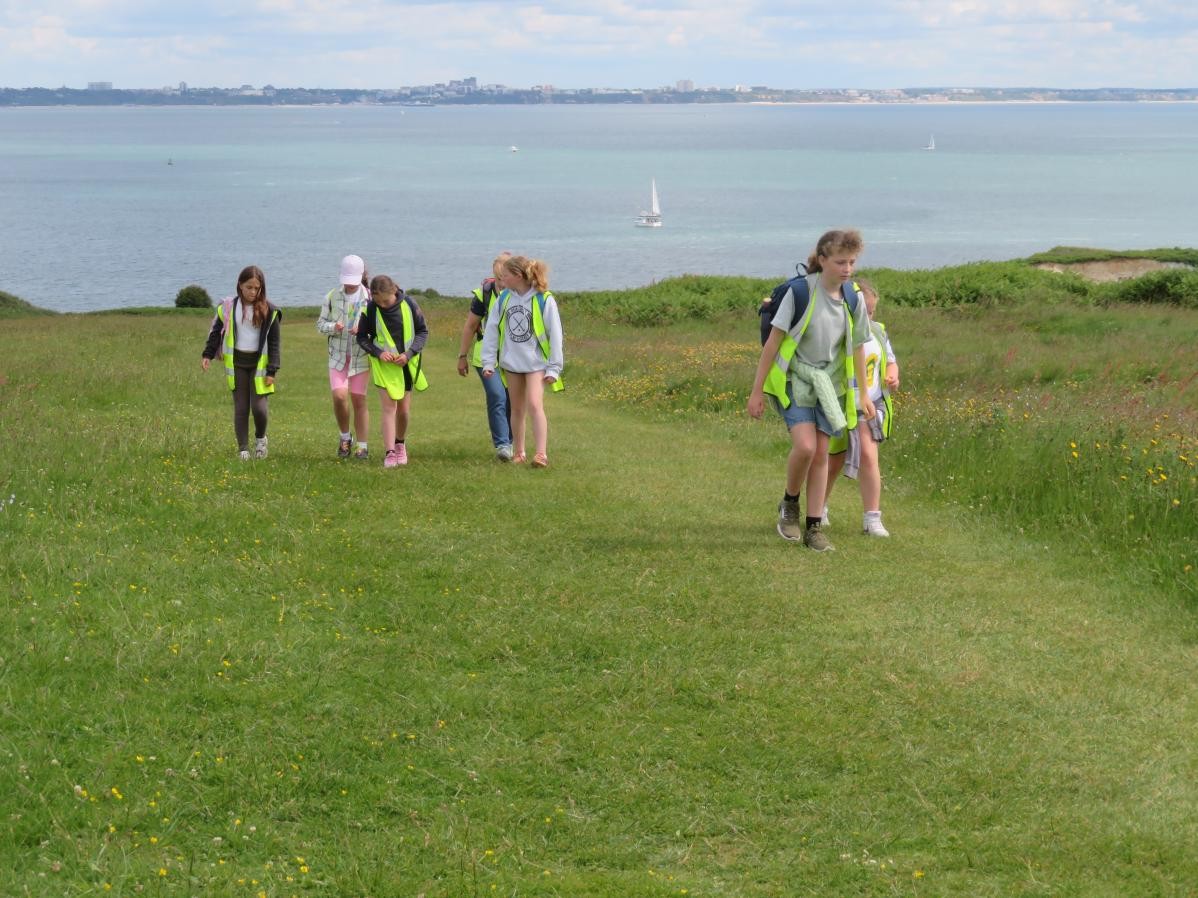 Children running across grass with the sea behind