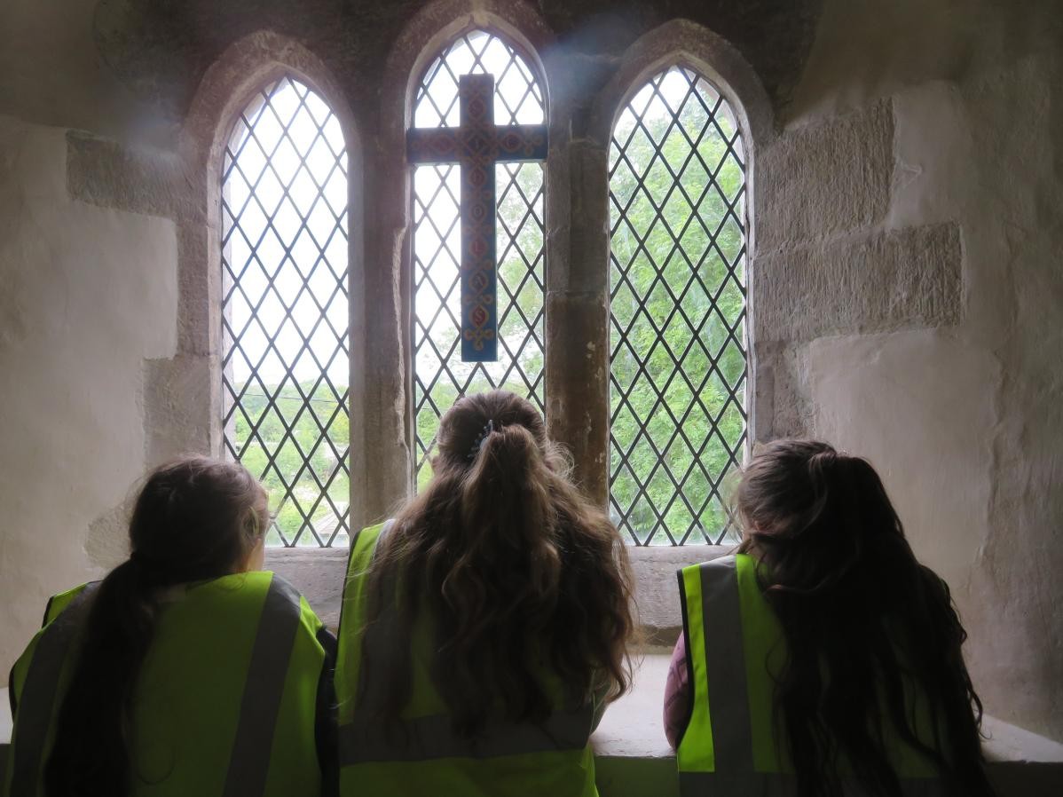 Photo taken from behind, 3 pupils in silhouette against church window