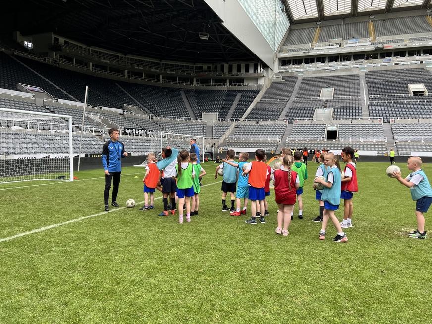 Pupils playing football on the pitch, at St James' Park!