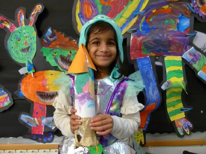 Smiling pupil sharing their colourful artworks