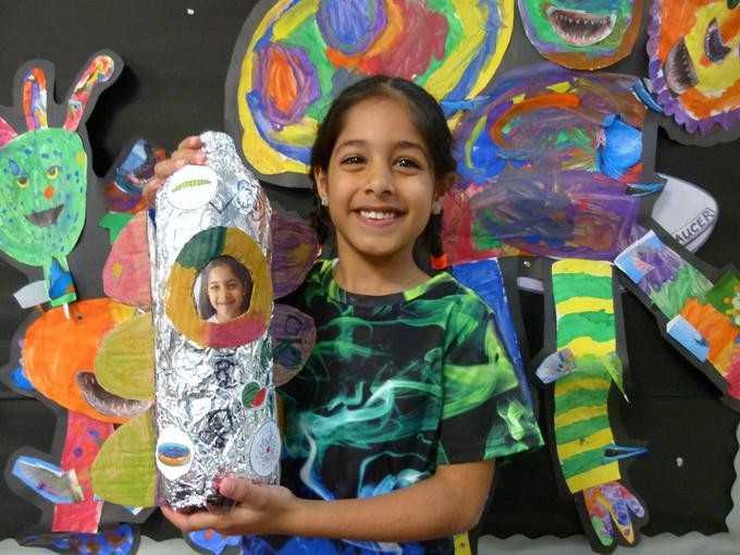 Smiling pupil sharing their colourful artworks