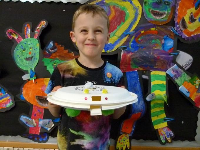 Smiling pupil sharing their colourful artworks