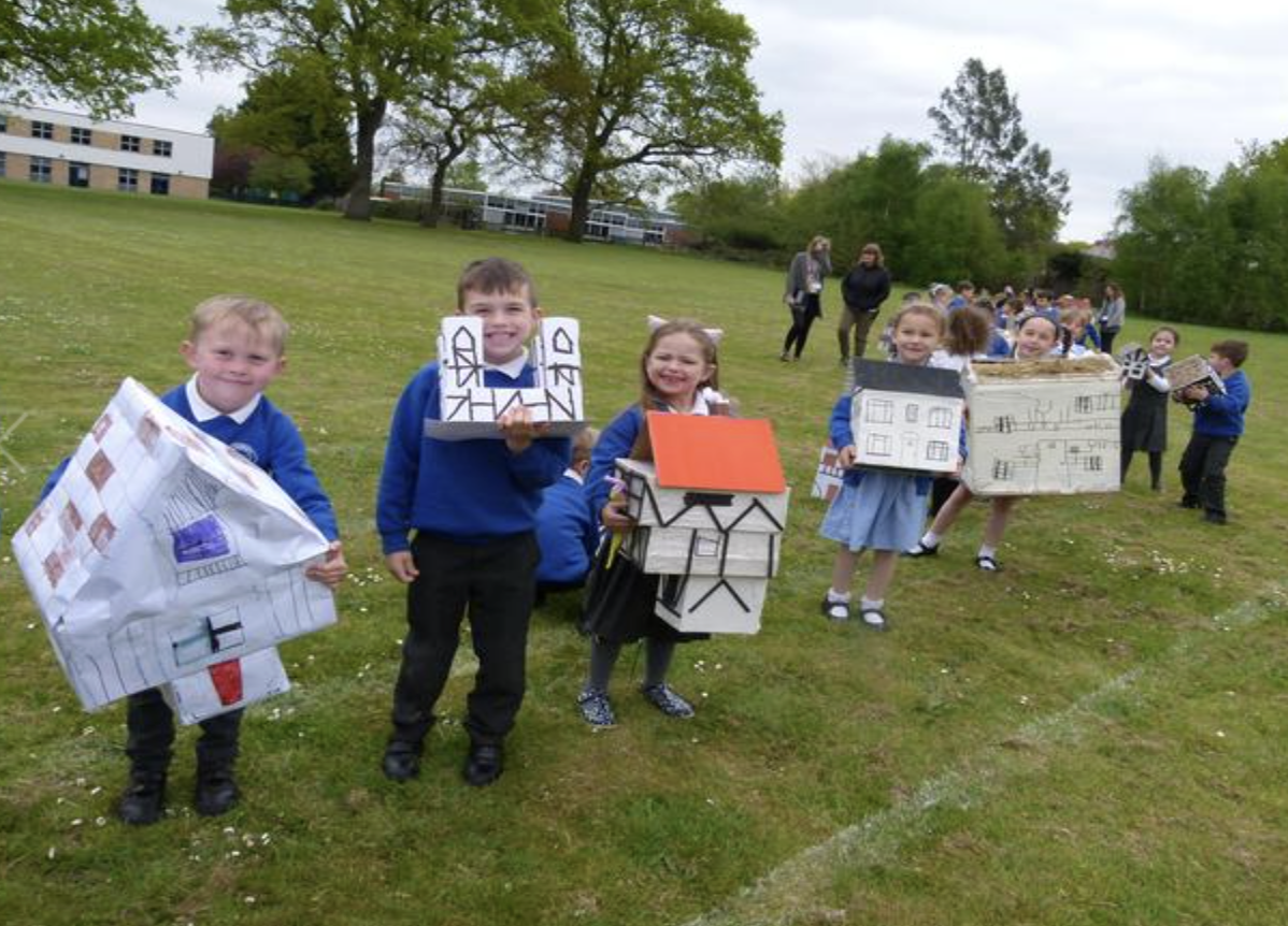 Pupils with card and paper models of houses on the school field