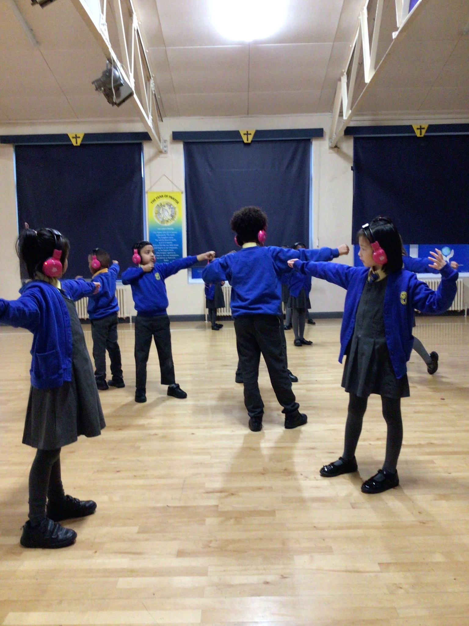 Children wearing ear defenders stood with arms outstretched 