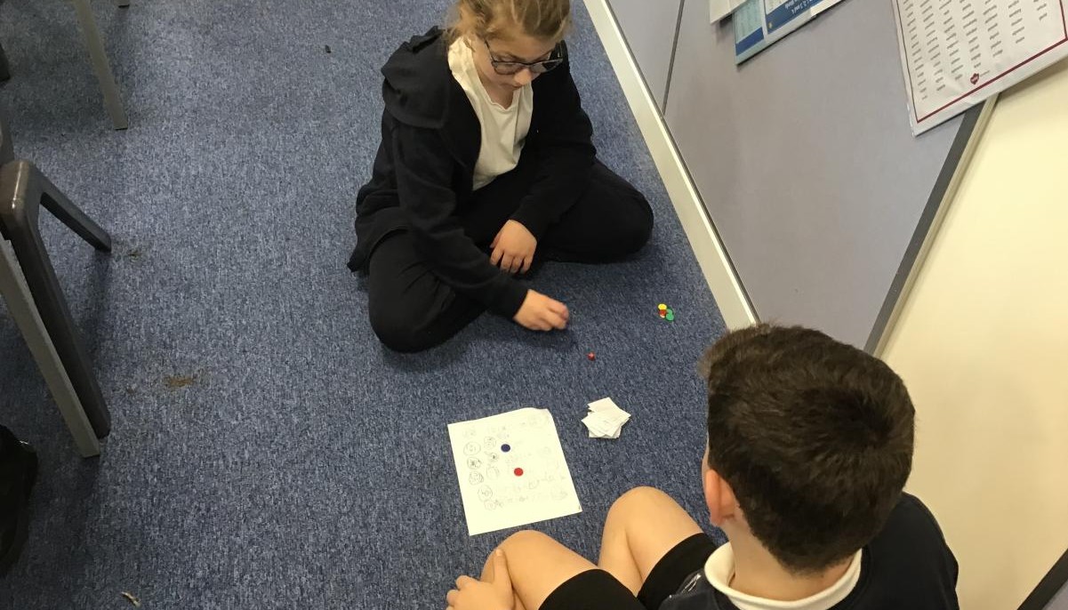 Two children sat opposite each other engaged in activity 