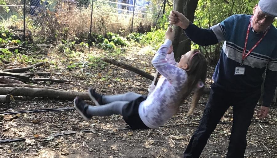 Child being pushed on rope swing