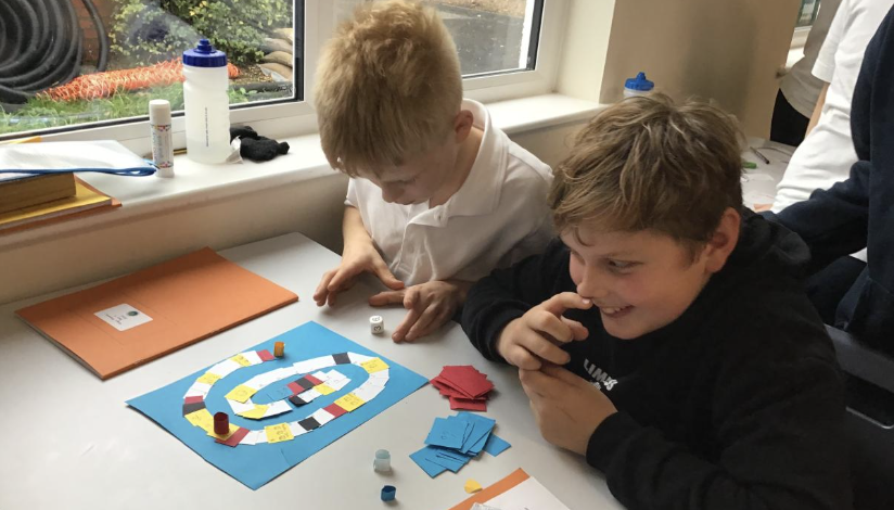 Two children sat a desk engaged in an activity 
