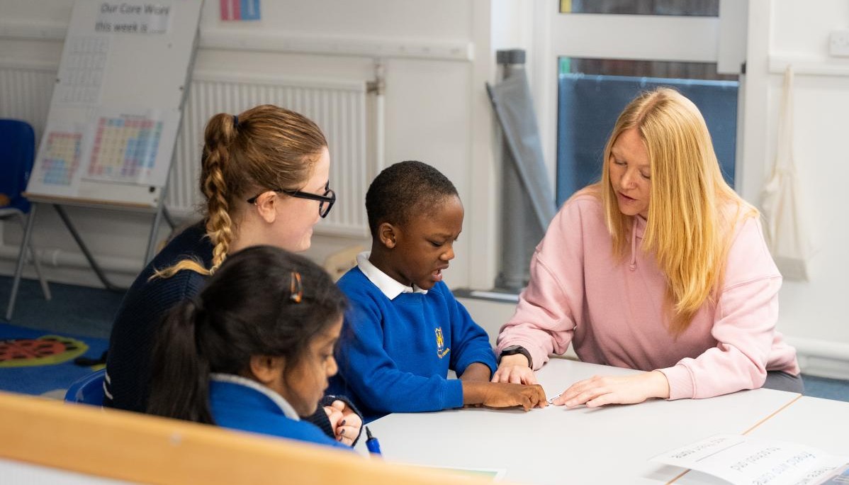 Two adults sat at a table alongside two children 