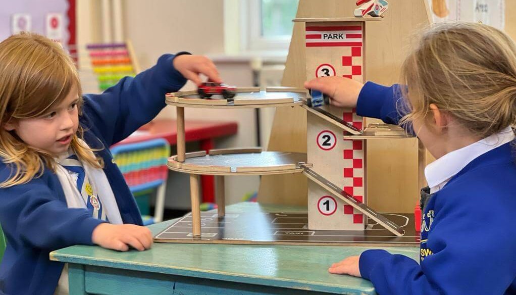 Two children playing with a wooden car garage