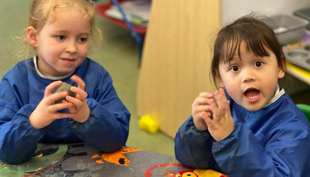 Two children holding playdough in their hands