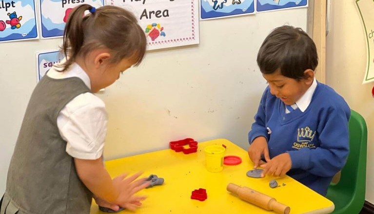 Two children sat at a table exploring playdough
