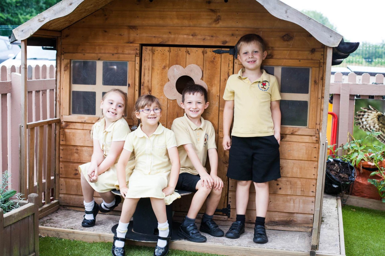 Smiling pupils outside wooden playhouse