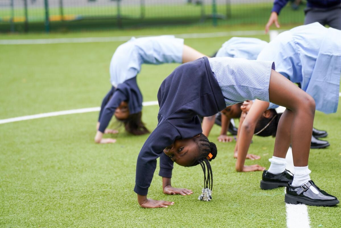 Pupils doing crab poses on the school field