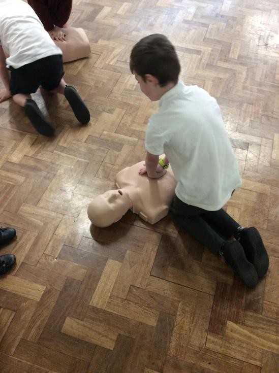 Child doing CPR on dummy