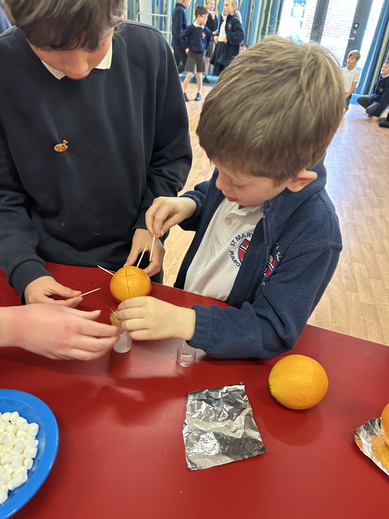 Our children buddy up to make Christingles