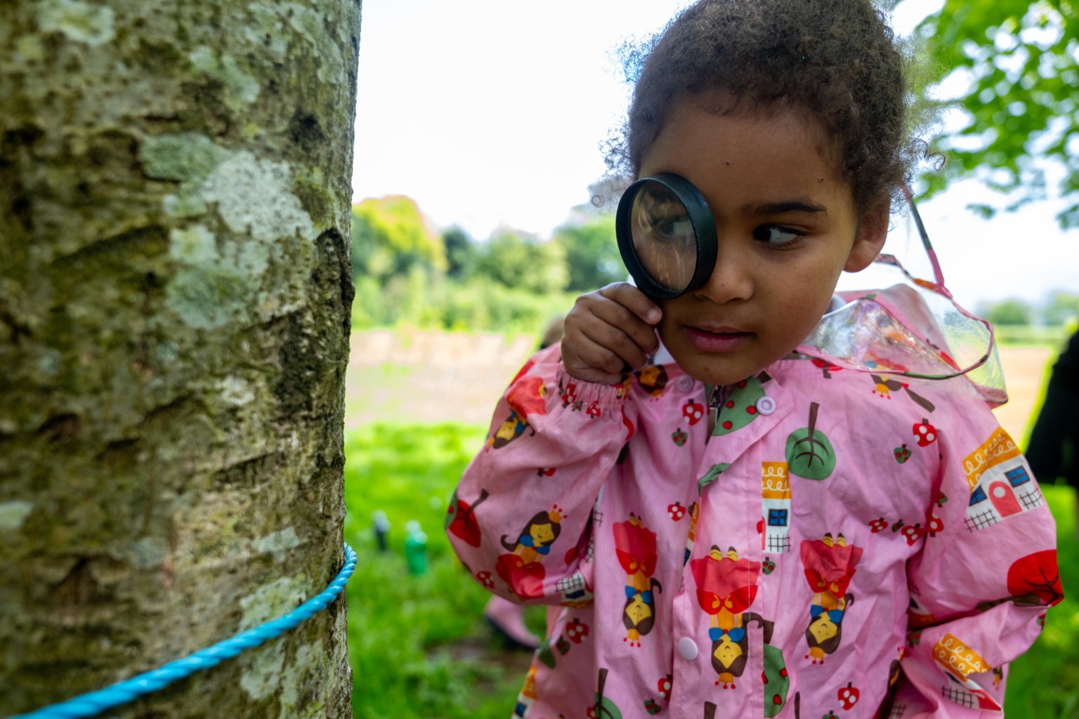 child looking through a magnifying glass outdoor