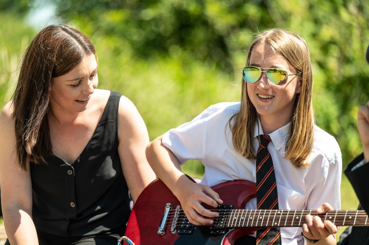 Pupil playing guitar outdoors