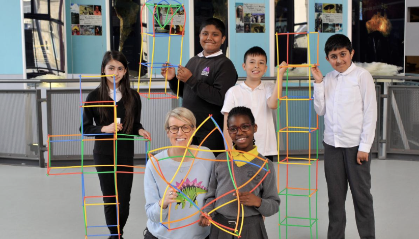children holding models they have made from coloured straws